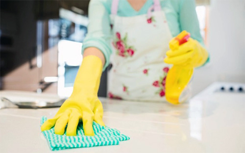 Mujer desinfectando la encimera de la cocina